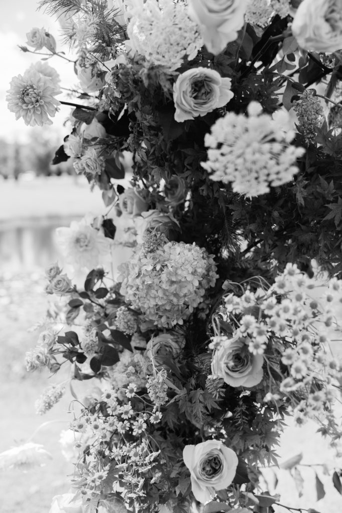 Black and white photo of hydrangeas and other flowers in wedding ceremony installation. 